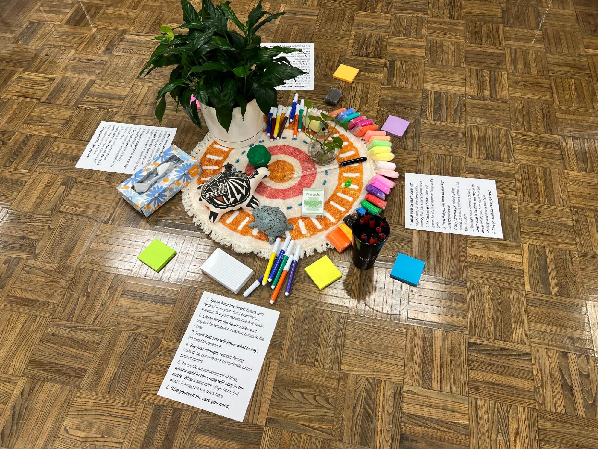 restorative justice materials, including post its and markers, laid out in a circle on the floor